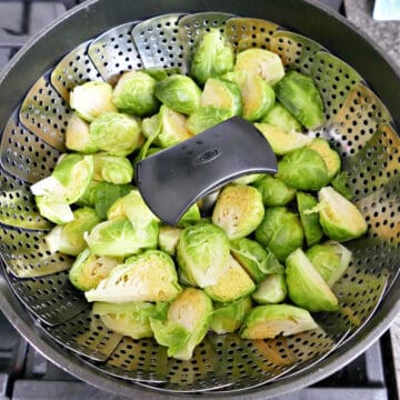 Brussels sprouts in a steamer basket over a pot on a stove