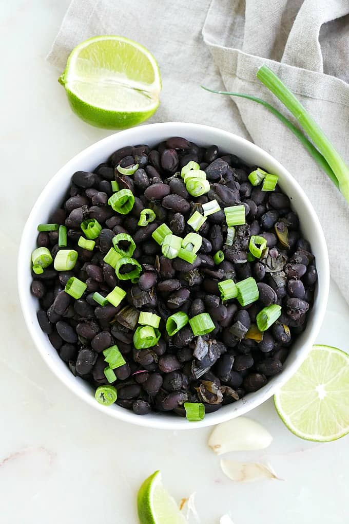 slow cooker black beans with scallions in a serving bowl on a counter