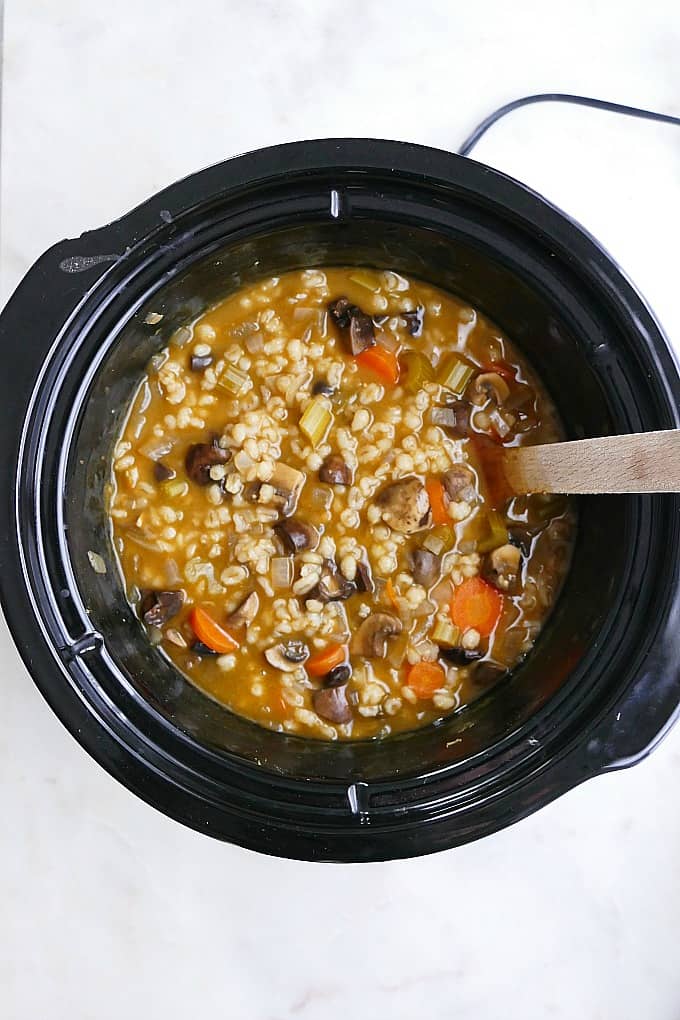 Mushroom Barley Stew in a crockpot with a wooden spoon