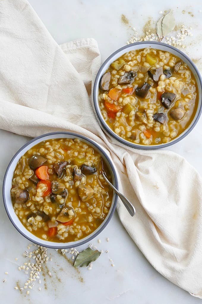 2 bowls of Mushroom Barley Stew in grey bowls on a white countertop