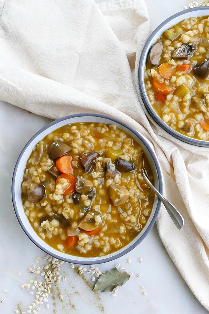 Mushroom Barley Stew in a grey bowl next to a white napkin on countertop