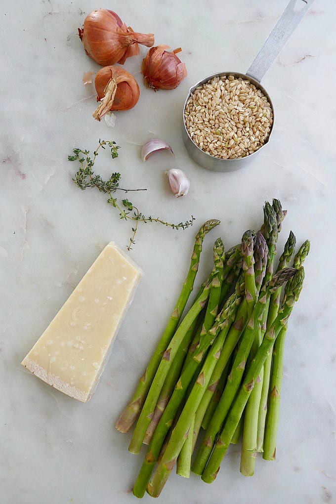 asparagus, parmesan, rice, garlic, shallots, thyme on a white counter