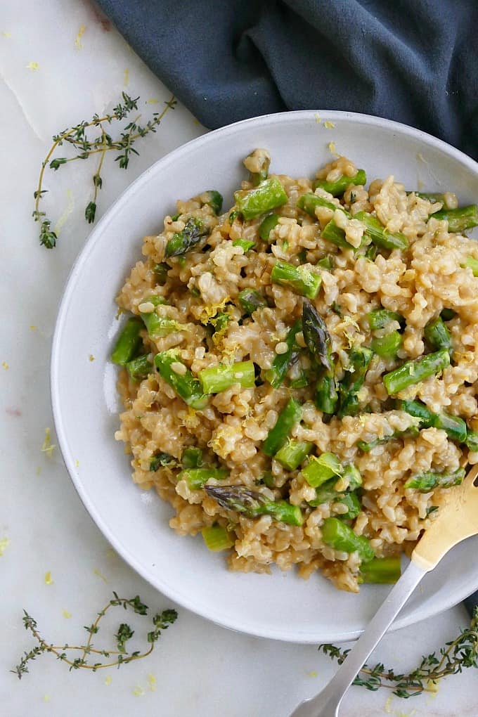 close up of baked brown rice risotto with asparagus on a white plate