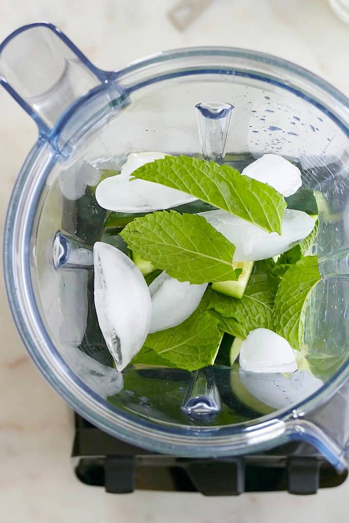 ingredients for a cocktail in a blender with ice and mint leaves