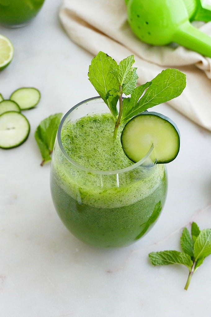 cucumber gin cocktail in a low glass garnished with cucumber slices and mint leaves