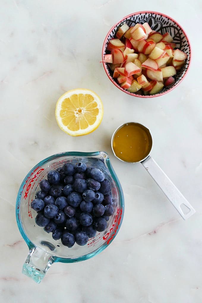 blueberries, rhubarb, lemon, and honey on a counter