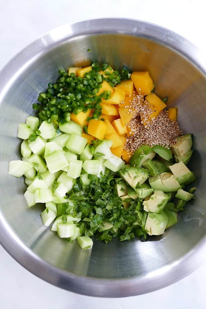 mango cucumber salad ingredients in a bowl on a counter
