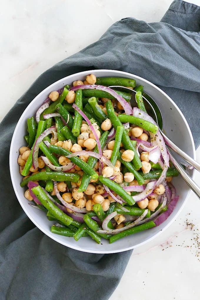 marinated green bean salad in a serving bowl with utensils on a counter