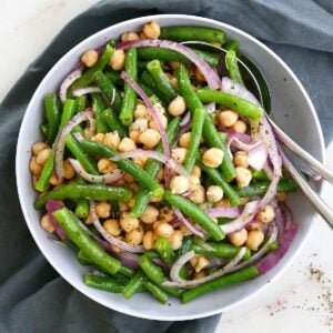 square image of Italian marinated green bean salad in a serving platter with utensils