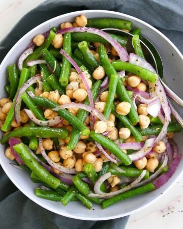 square image of Italian marinated green bean salad in a serving platter with utensils