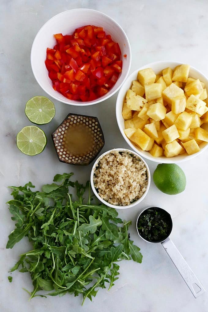 bell pepper, pineapple, quinoa, arugula, lime, mint, and honey on a counter