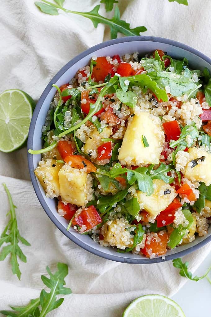 close up of quinoa arugula salad with pineapple in a bowl on a counter