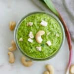 Ramp pesto in a glass jar topped with roughly chopped cashews.