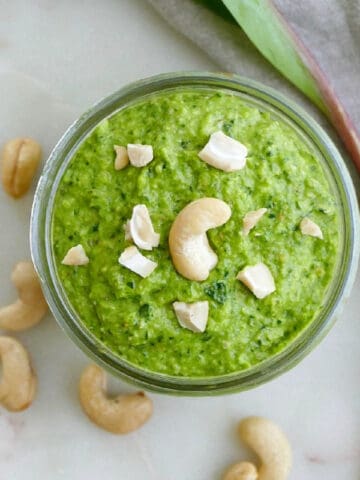 Ramp pesto in a glass jar topped with roughly chopped cashews.