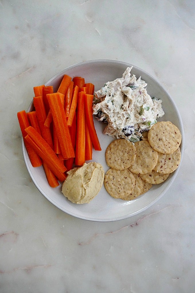 plate with carrots, chicken salad, hummus, crackers