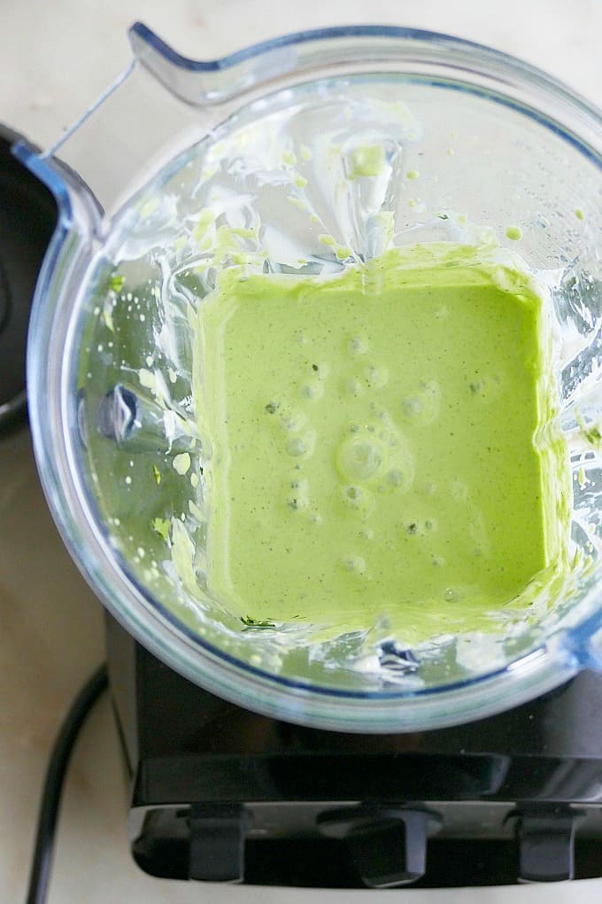 a blended green dressing in a blender on a counter