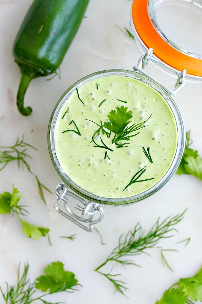 creamy jalapeno sauce topped with herbs in a glass jar