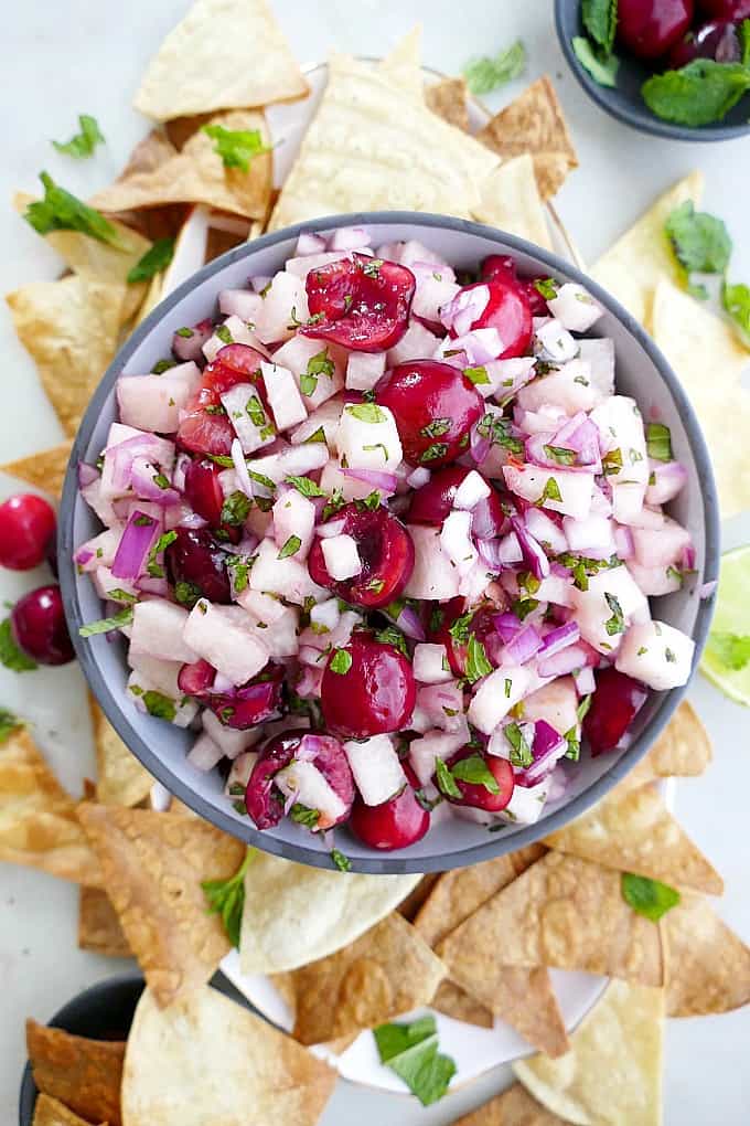 jicama cherry salsa in a serving bowl surrounded by chips on a platter