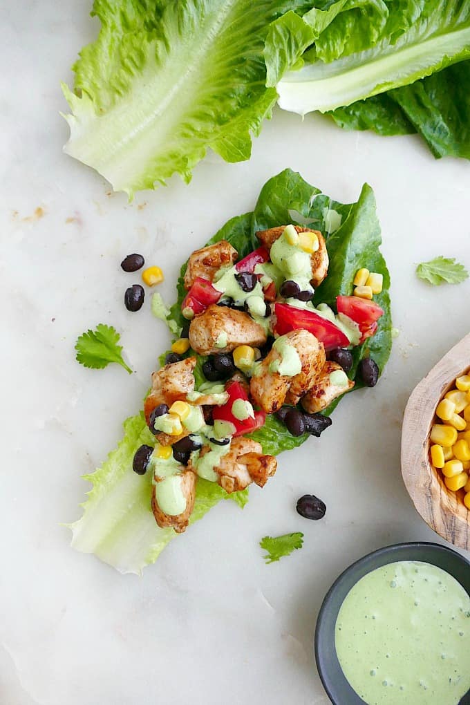 one chicken lettuce wrap topped with corn, tomatoes, beans, and jalapeno sauce