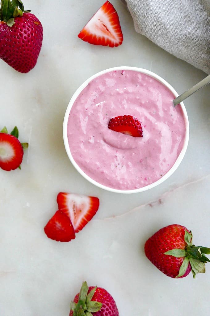 strawberry tahini dressing in a small white bowl with a spoon on a counter