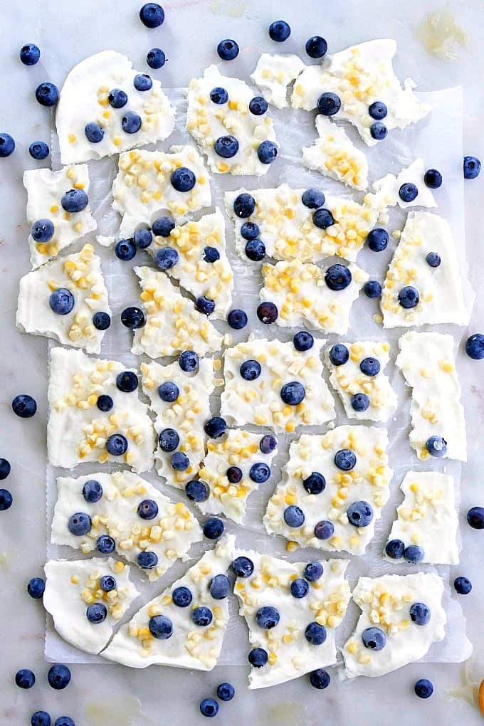 broken frozen yogurt bark spread out on parchment paper on a counter