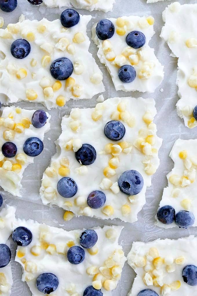 pieces of blueberry sweet corn frozen greek yogurt bark spread out on parchment paper
