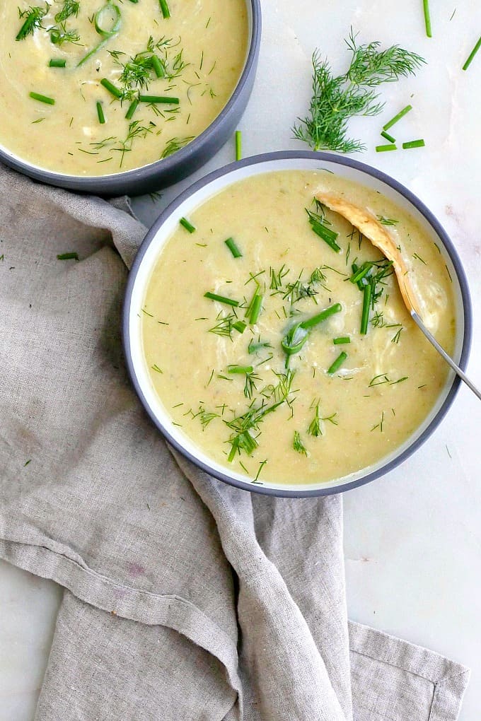 bowl of potato garlic scape soup with a spoon on a counter next to a napkin