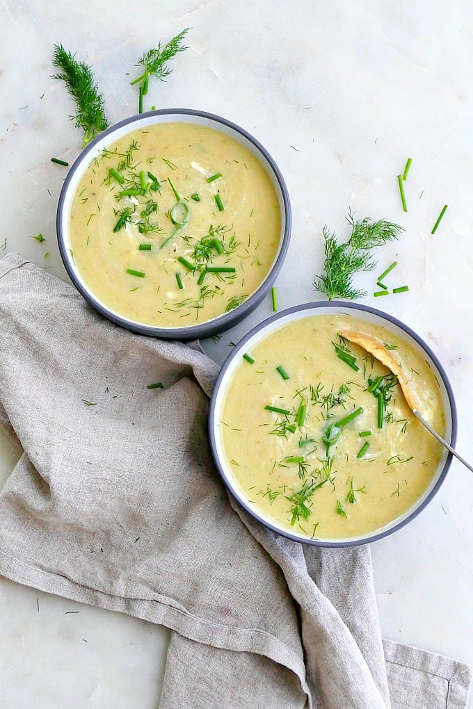 two bowls of soup next to a napkin and garnished with herbs