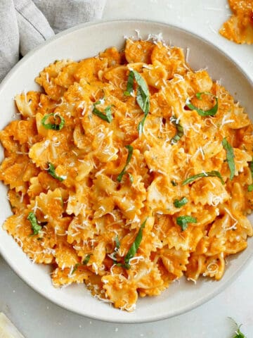 bowtie pasta covered with roasted red pepper sauce in a serving dish