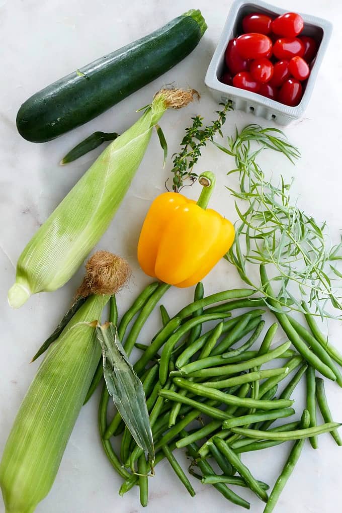 zucchini, corn, bell pepper, green beans, tarragon, tomatoes, and herbs on a counter