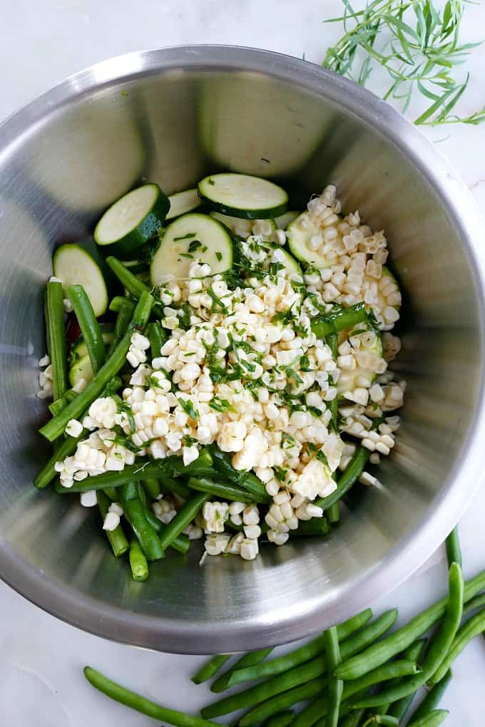 green beans, corn kernels, and herbs in a bowl on a counter