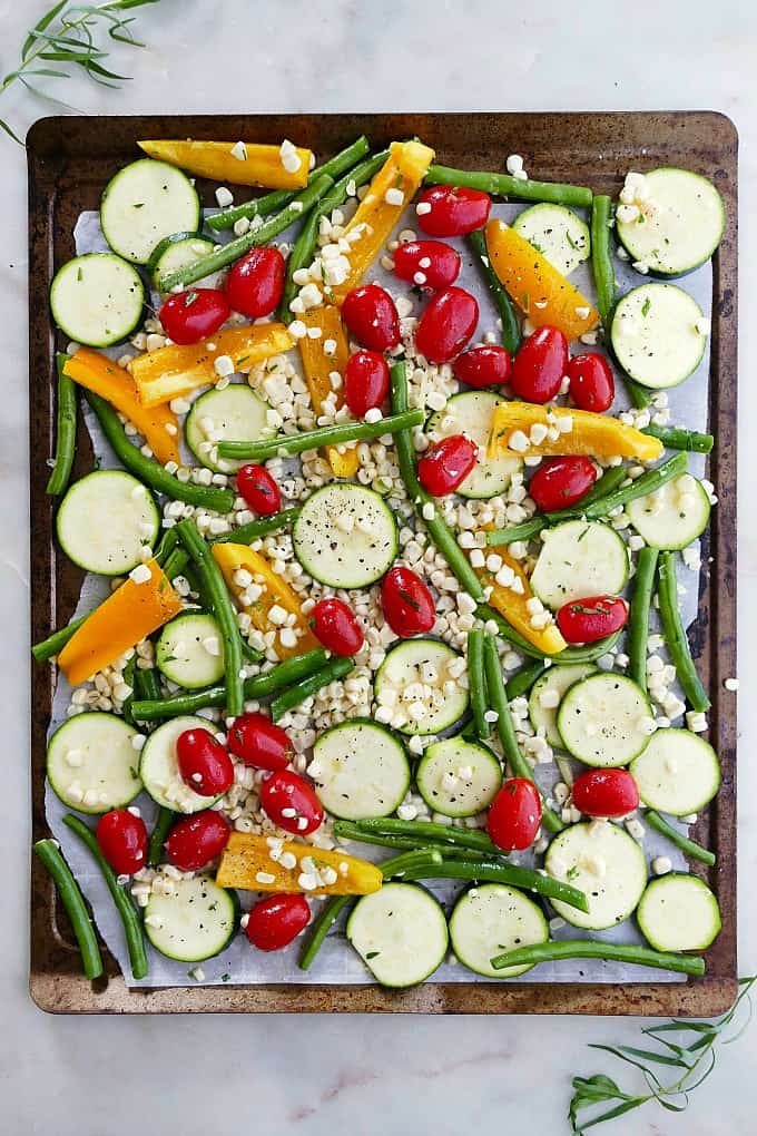 summer vegetables spread out on a baking sheet lined with parchment paper
