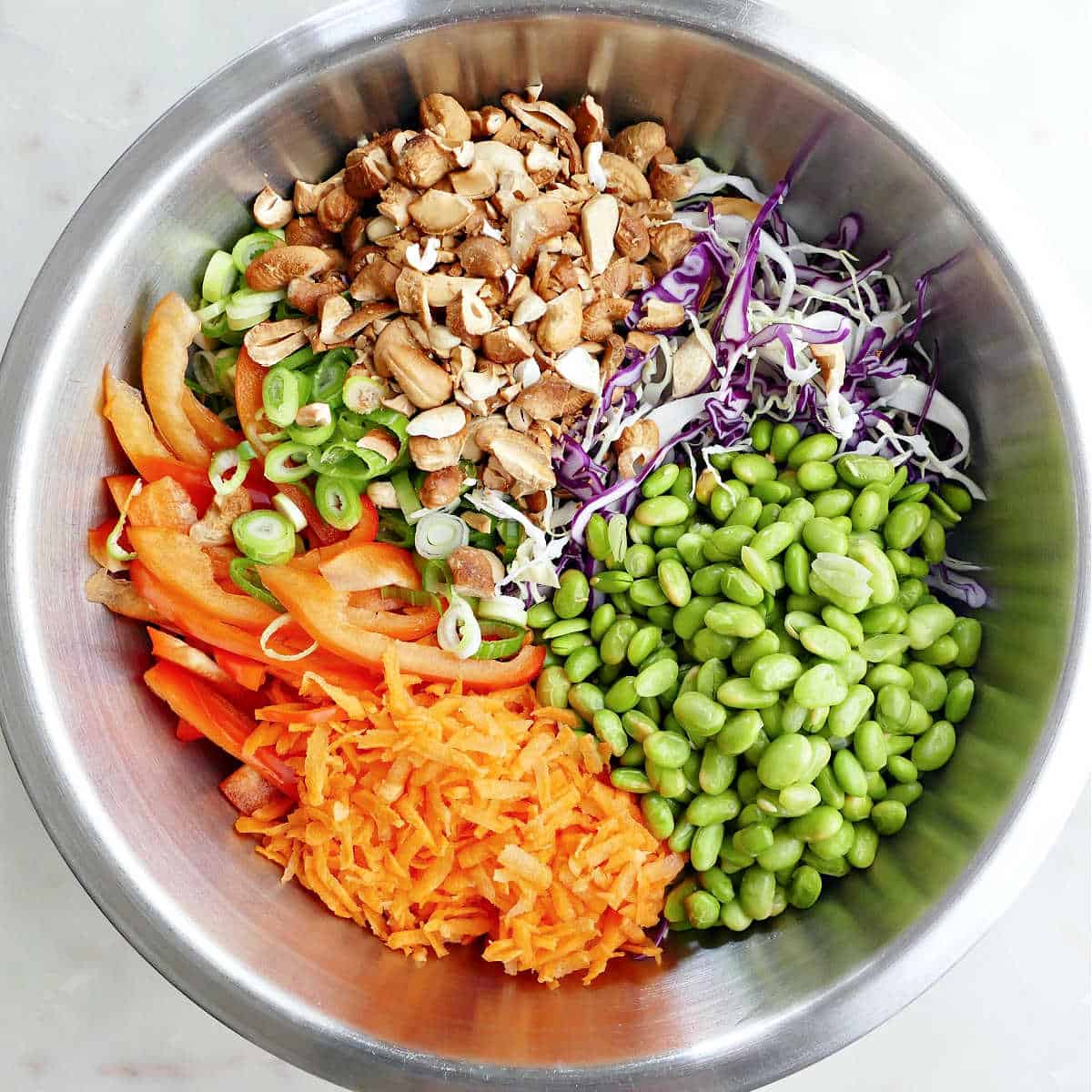 carrots, bell pepper, green onion, cashews, cabbage, and edamame in a mixing bowl