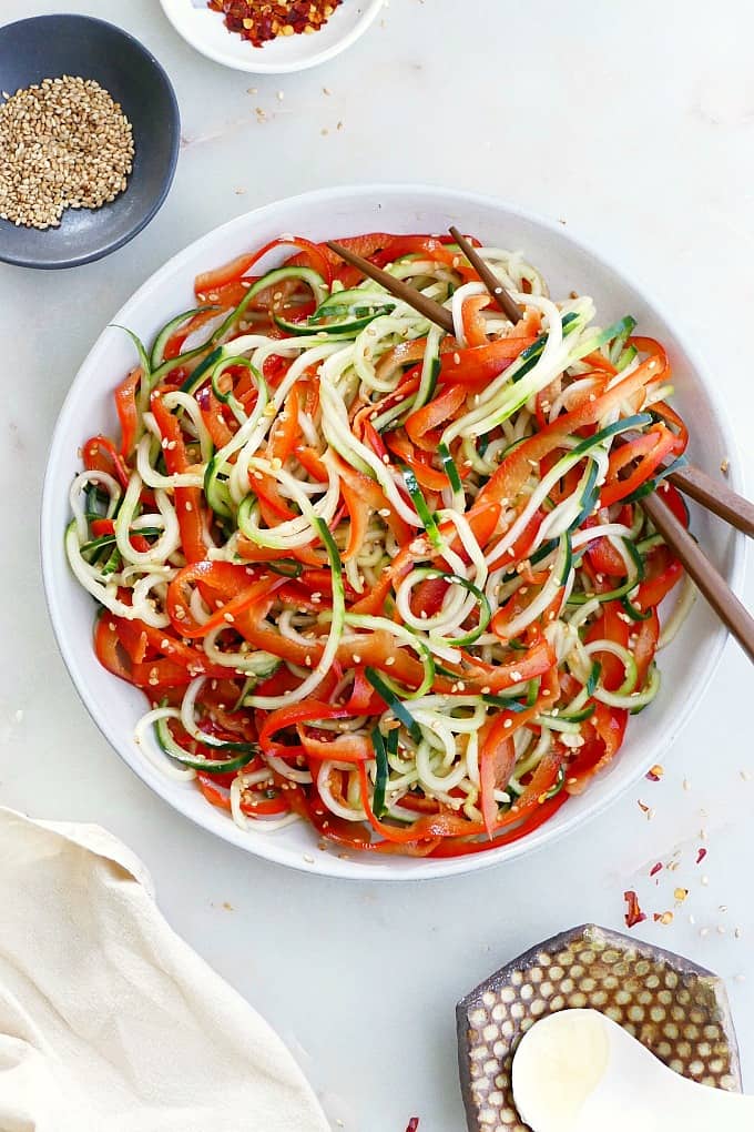 bell pepper and cucumber noodle salad on a serving plate with chopsticks