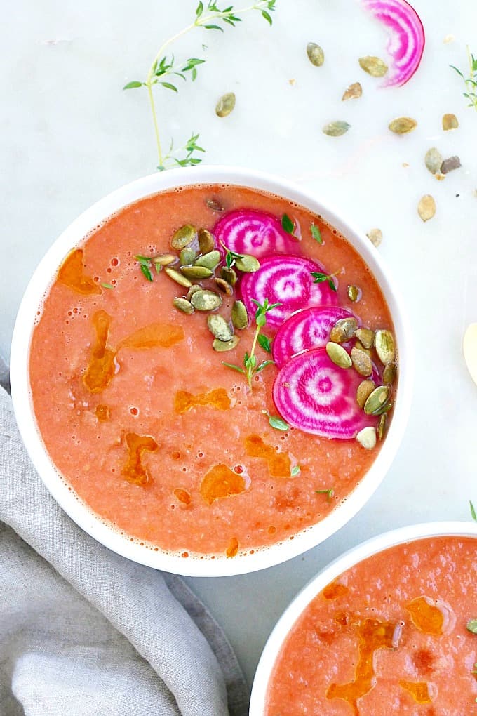 bowl of beet gazpacho with sliced beets, seeds, and herbs on top