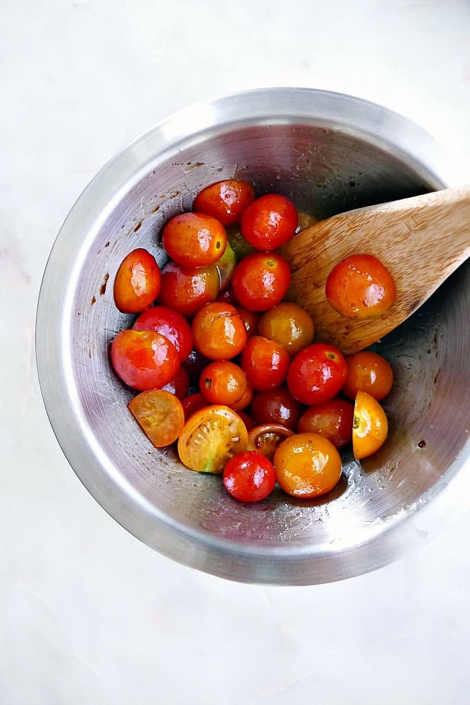 tomatoes in a mixing bowl tossed in balsamic vinegar