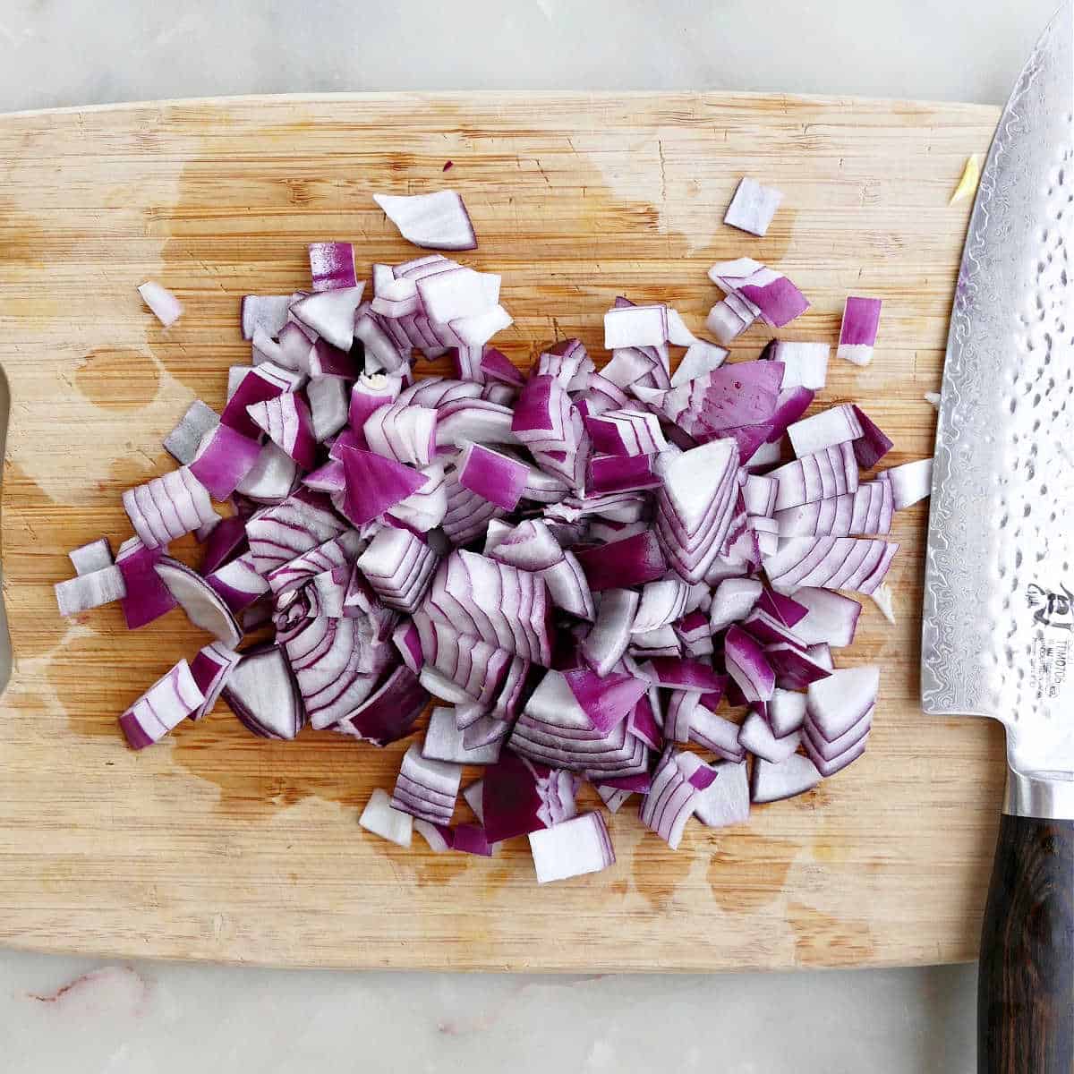 red onion diced into pieces on a cutting board next to a knife
