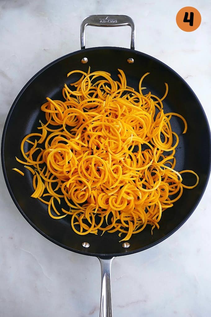 butternut squash noodles cooked in oil in a black skillet on a white counterop