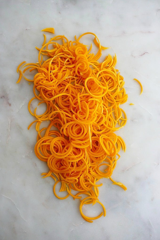 thinly spiralized butternut squash noodles on a marble countertop