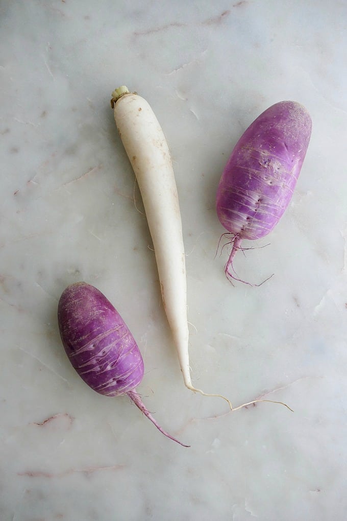 white and purple daikon radishes on a white marble countertop