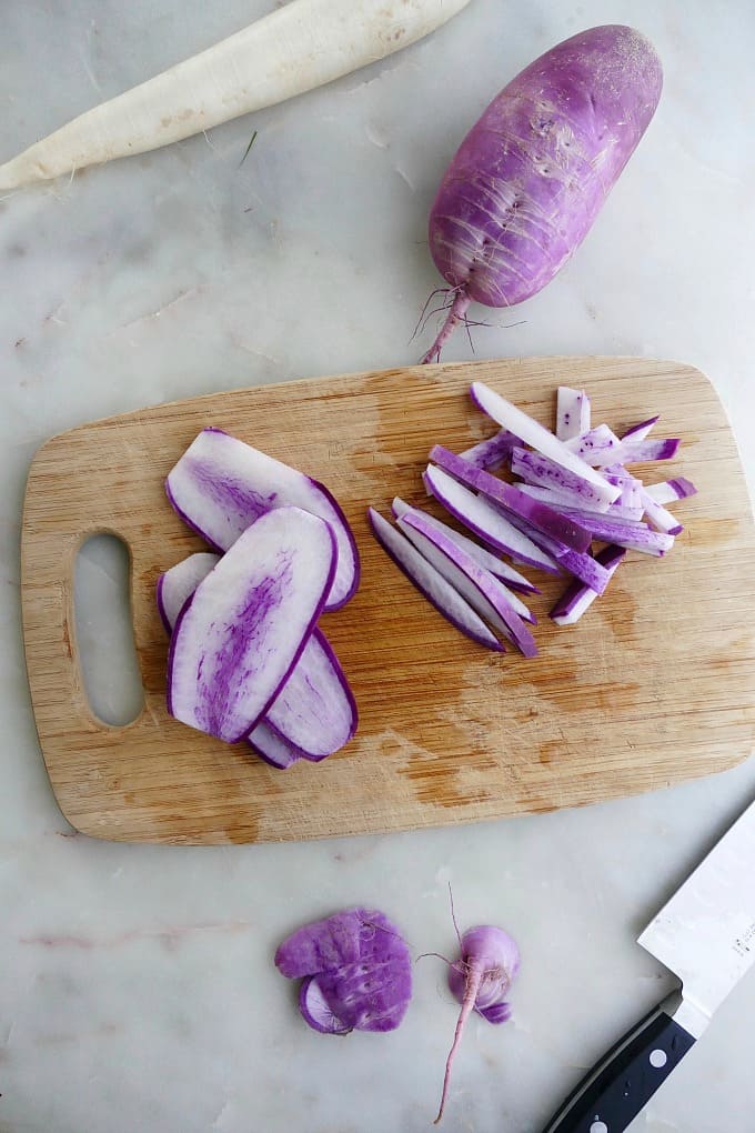 sliced purple daikon radish on a bamboo cutting board