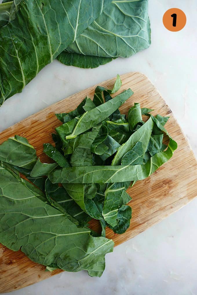 collard greens sliced into ribbons on a bamboo cutting board