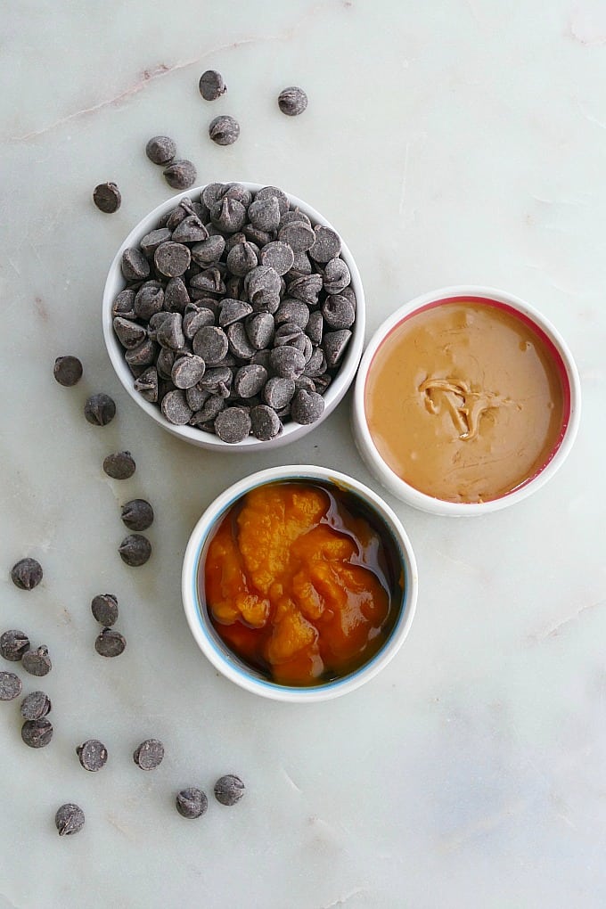 chocolate chips, peanut butter, and pumpkin in small bowls on countertop