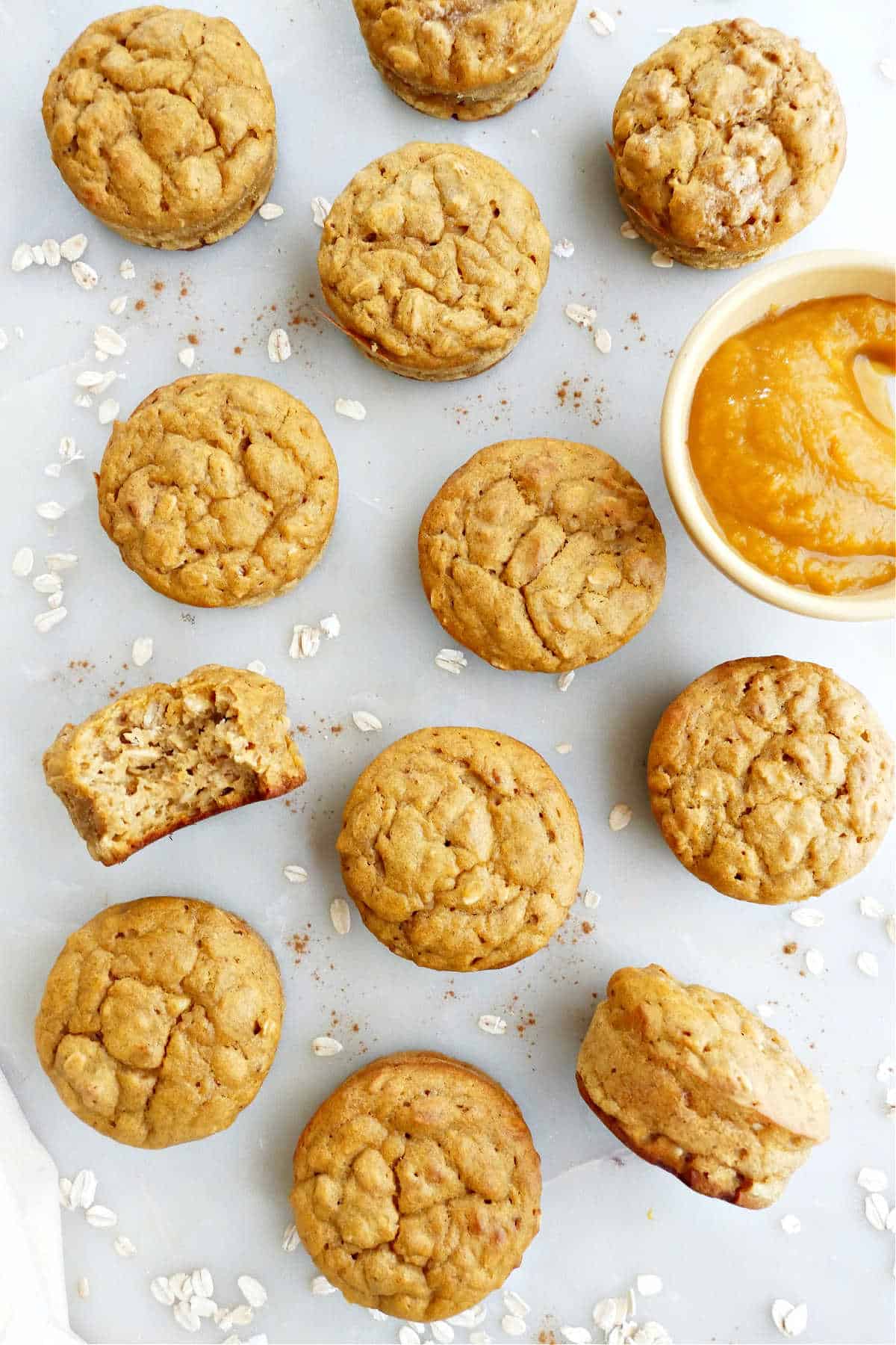 7 butternut squash muffins on a white plate with oats and cinnamon on top