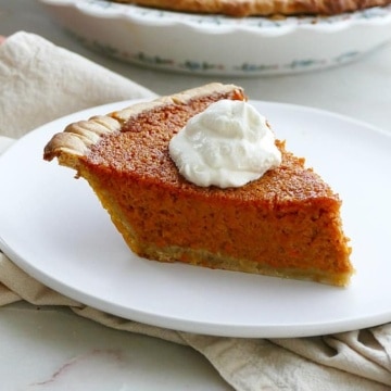 side view of a slice of carrot pie with a dollop of whipped cream