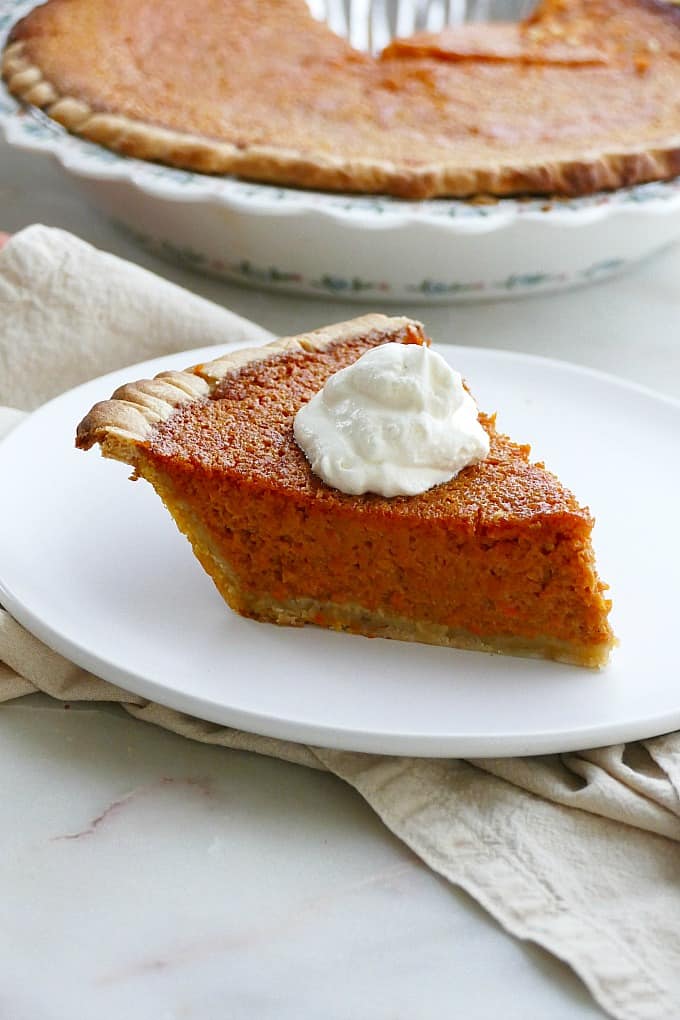 side view of a slice of carrot pie with a dollop of whipped cream