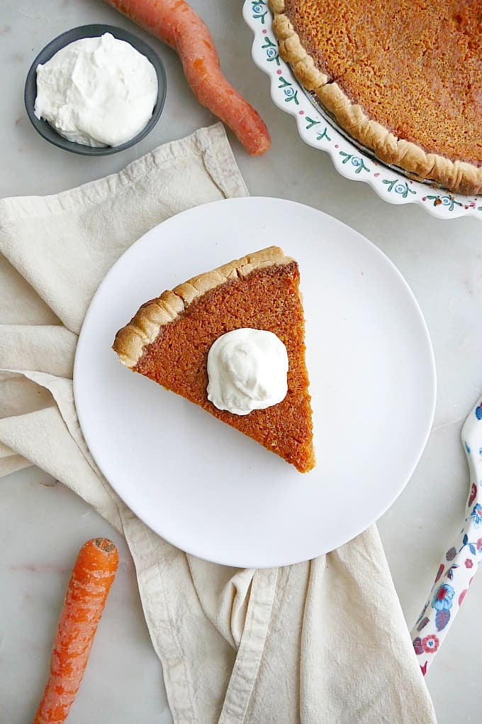 slice of carrot pie with whipped cream on a white plate