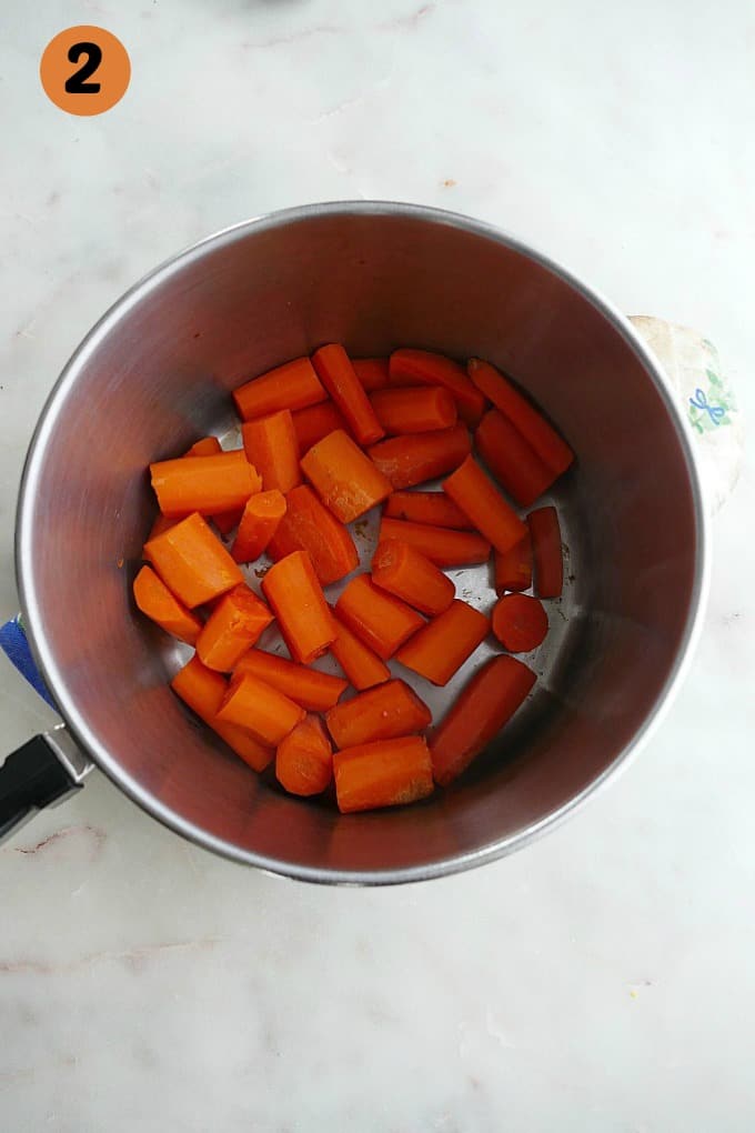 chopped carrots in a small saucepan on a white counter