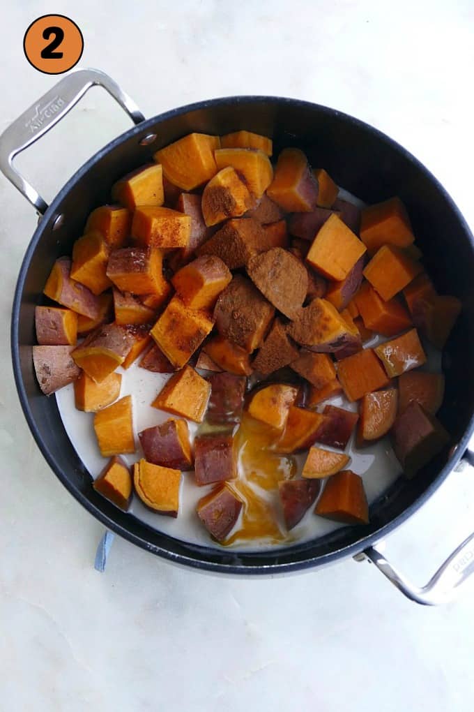 diced sweet potatoes, spices, eggs, and coconut milk in a black pot on a counter