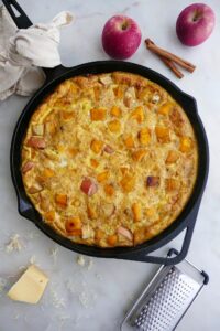 apple pumpkin frittata with gouda in a black skillet on a countertop